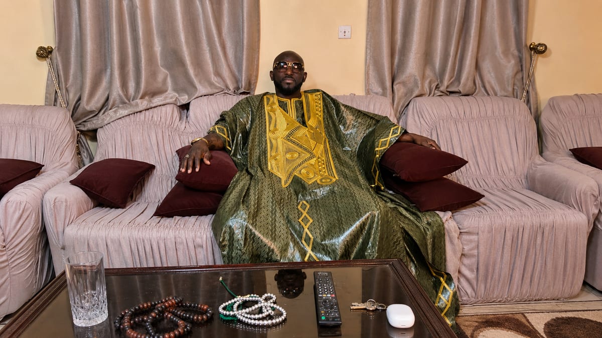 Marabout Djibril in boubou verde e oro, con i rosari posati davanti